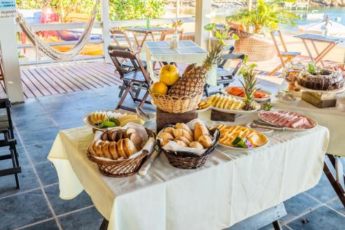 a table with baskets of bread and fruit on it at Pousada e Mergulho Dolce Vita in Praia Vermelha