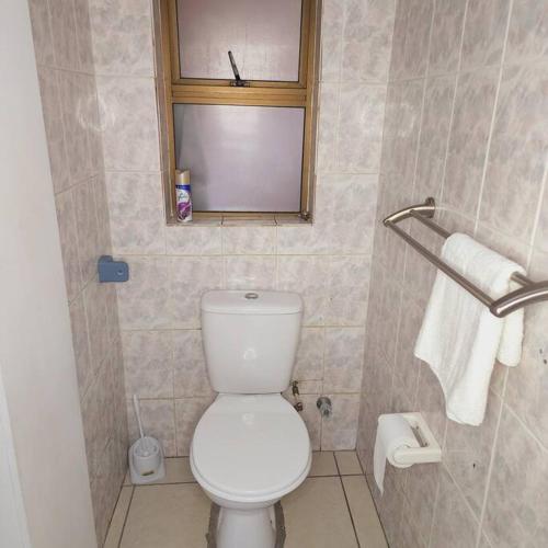 a bathroom with a white toilet and a window at Mercy's Getaway Place in Cape Town
