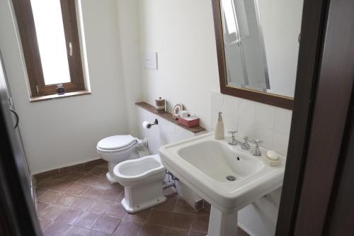 a white bathroom with a toilet and a sink at Casa delle Macine in Caltanissetta