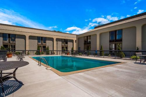 a swimming pool with tables and chairs in front of a building at Clarion Inn & Suites Grand Rapids Airport in Grand Rapids
