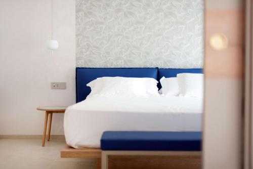 a bed with a blue headboard and white pillows at Hotel Globus Pool & Beach in Milano Marittima