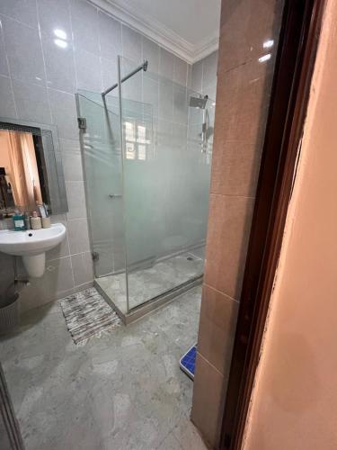 a bathroom with a glass shower with a sink at House Ire in Abuja