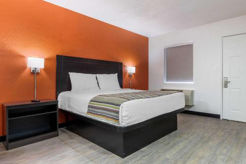 a bedroom with a bed with an orange wall at Suburban Studios Spartanburg - I-26 in Spartanburg