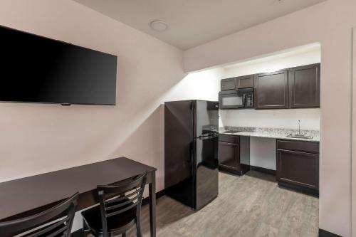 a kitchen with a table and a black refrigerator at Suburban Studios Spartanburg - I-26 in Spartanburg
