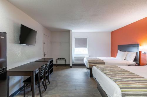a hotel room with two beds and a desk at Suburban Studios in Spartanburg