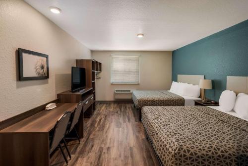 a hotel room with two beds and a television at WoodSpring Suites West Palm Beach in West Palm Beach