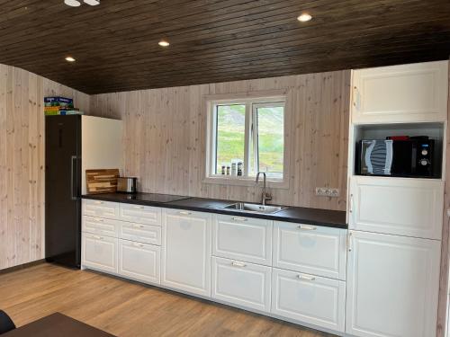 cocina con armarios blancos y encimera negra en Strönd Guesthouse, en Birkimelur 