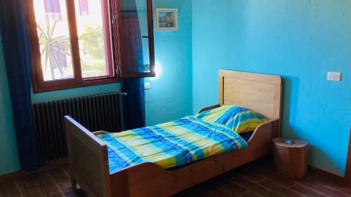 Cama pequeña en habitación azul con ventana en Il Rustico, en Fluminimaggiore