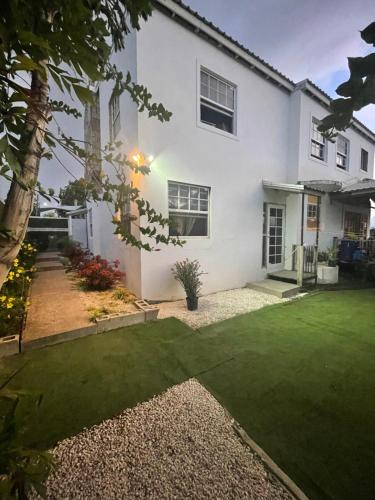 a white house with a green lawn in front of it at Scarlett Studios - Holiday-Business-US Embassy Appt 7 mins drive away - The one night only rate includes Airport and Embassy transportation in Bridgetown