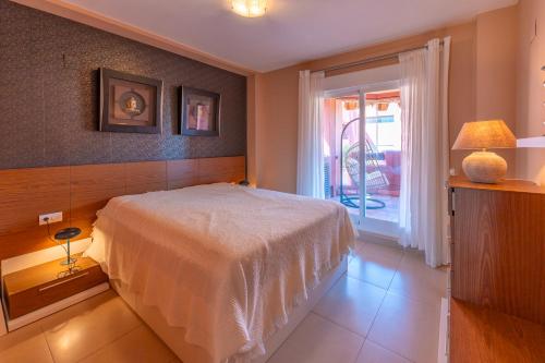 a bedroom with a white bed and a sliding glass door at Apartamento Punta del Faro in Torrox Costa
