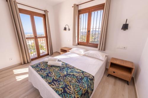 a bedroom with a bed and two large windows at Apartamento Chic in Frigiliana