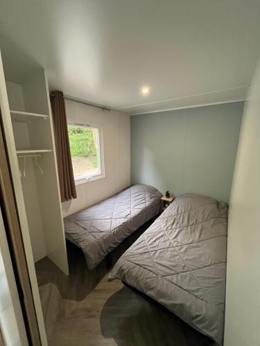 deux lits dans une petite pièce avec une fenêtre dans l'établissement Mobil home climatisé, à Lège-Cap-Ferret