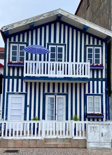 a blue and white house with a balcony and an umbrella at Palheiro da Ana in Costa Nova