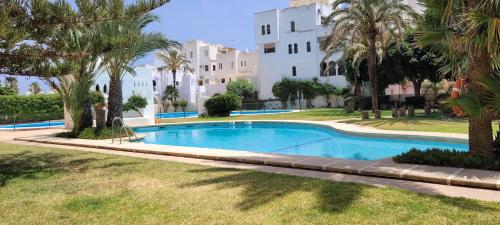 uma piscina com palmeiras em frente a um edifício em Roquetas de mar em Roquetas de Mar