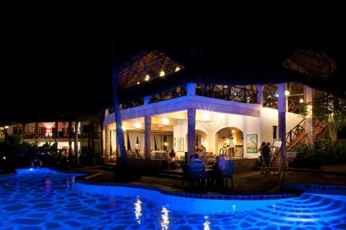 a resort with a swimming pool at night at Aquarius Club in Watamu