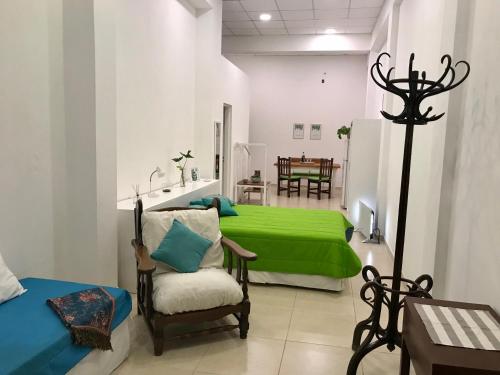a room with a green bed and a chair at Costanera in San Nicolás de los Arroyos