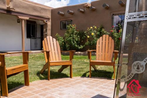 two wooden chairs sitting in front of a house at Rancho de La Luna Casita in Santa Fe