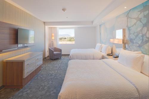 a hotel room with two beds and a flat screen tv at Courtyard by Marriott Saltillo in Saltillo