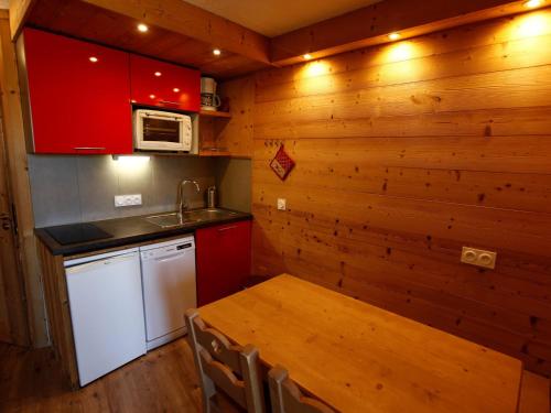 une cuisine avec des placards rouges et une table en bois dans l'établissement Appartement rénové 4 personnes avec balcon, centre Avoriaz, ski et commerces à proximité - FR-1-314-138, à Avoriaz