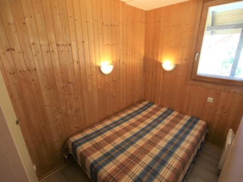 Cette petite chambre comprend un lit dans un mur en bois. dans l'établissement Appartement 2 pièces cabine 6 pers avec balcon à Avoriaz, WIFI - FR-1-314-146, à Avoriaz