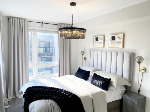 a white bedroom with a large bed with a chandelier at Modern and Bright Luxury Home Centrally Located in Toronto’s GTA in Toronto