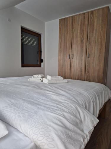 a bedroom with a large white bed with wooden cabinets at Apartmani Milosavljević in Kuršumlija