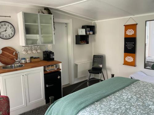 a bedroom with a bed and a sink and a clock at Orange Tree Cottage - garden hideaway in Whanganui