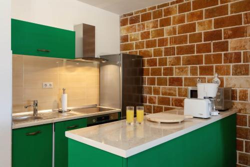 uma cozinha com armários verdes e uma parede de tijolos em Family friendly house with a swimming pool Pucisca, Brac - 21243 em Pučišća
