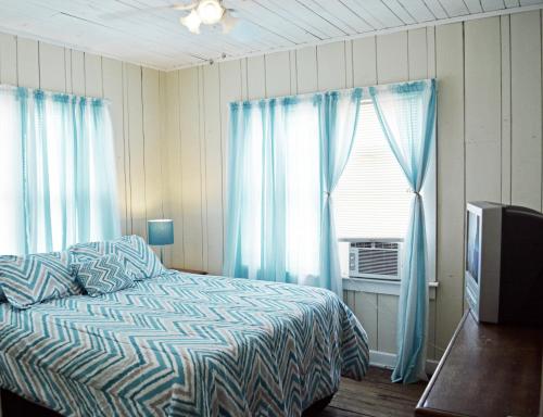 a bedroom with a bed and a window with blue curtains at Sunshine Cozy Cottage in Clearwater Beach