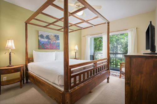 a bedroom with a canopy bed and a balcony at Aston At Poipu Kai in Koloa