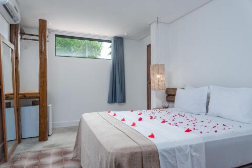 a bedroom with a bed with red rose petals on it at Vila Anauá in Japaratinga