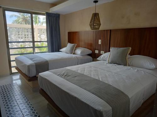 a hotel room with two beds and a window at Hotel Yaxactun in Progreso