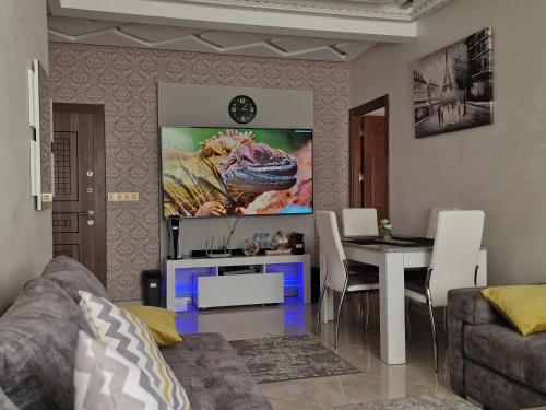 a living room with a table and a lizard on the wall at Fabuleux Appart a Larache avec confort exceptionnel et propreté souhaitée in Larache