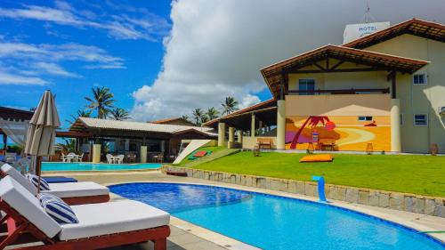 ein Pool mit Stühlen und ein Haus mit Spielplatz in der Unterkunft Sunset Beach Hotel in Taíba