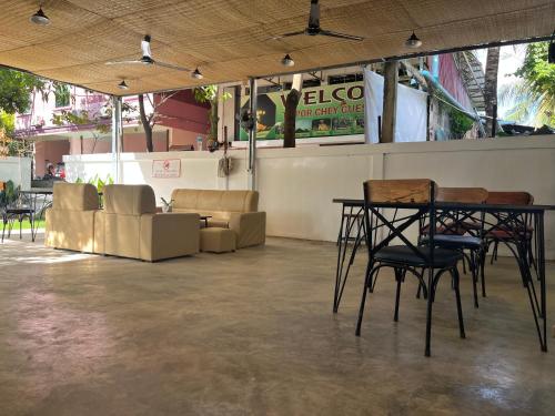 Zimmer mit einem Tisch, Stühlen und einem Sofa in der Unterkunft Por Chey Hostel in Battambang