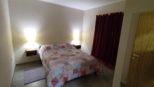 een kleine slaapkamer met een bed en 2 lampen bij Cabañas Berenice in Malargüe