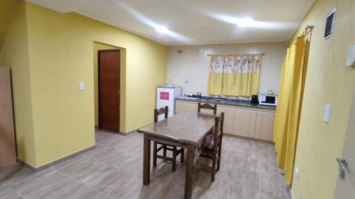 een keuken met gele muren en een houten tafel bij Cabañas Berenice in Malargüe