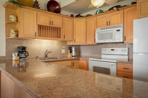 a kitchen with wooden cabinets and a counter top at Aston At Poipu Kai in Koloa