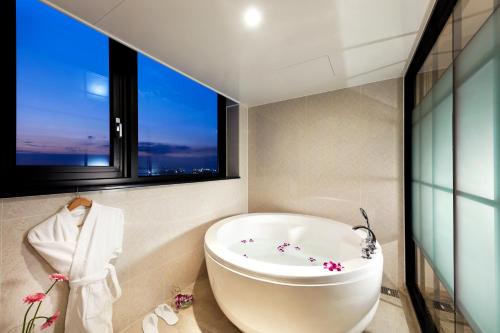 a bathroom with a bath tub and a window at Pyeongtaek K-tree Hotel in Pyeongtaek