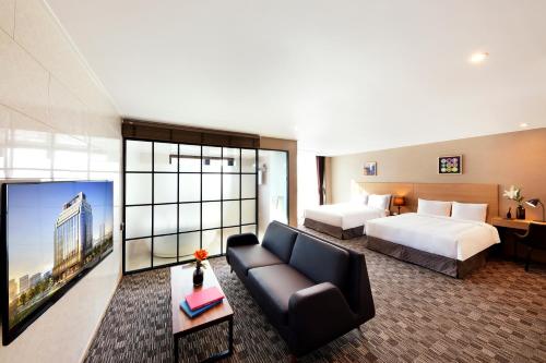 平沢市にあるPyeongtaek K-tree Hotelのベッドとソファ付きのホテルルーム