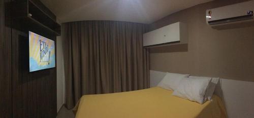 a hotel room with a yellow bed and a window at Manawa Beach Flat A24 - Centro Porto de Galinhas in Porto De Galinhas