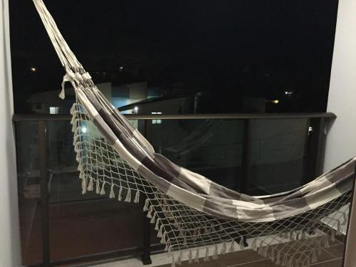 a hammock hanging from a window with a table at Manawa Beach Flat A24 - Centro Porto de Galinhas in Porto De Galinhas