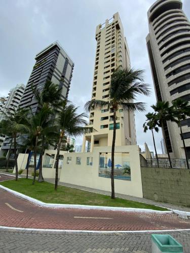 two tall buildings and palm trees in a street at Flat Beira Mar Piedade in Recife
