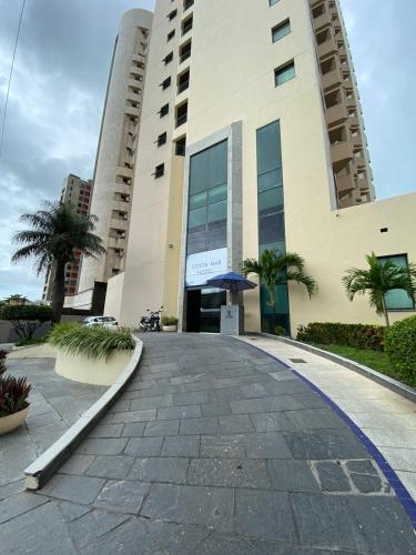 a walkway in front of a building with palm trees at Flat Beira Mar Piedade in Recife