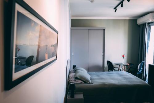 a bedroom with a bed and a picture on the wall at Flat BOUTIQUE em frente ao metrô MOEMA in São Paulo