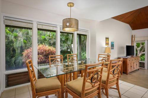 a dining room with a glass table and chairs at Aston At Poipu Kai in Koloa