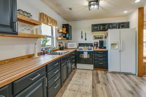 a kitchen with black cabinets and a white refrigerator at Charming Smiths Grove Home Near Cave Tours! in Smiths Grove