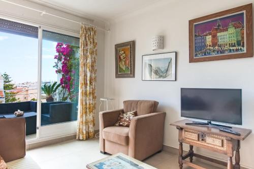 - un salon avec une télévision à écran plat et une chaise dans l'établissement Fleurs de Nice furnished flat, à Nice