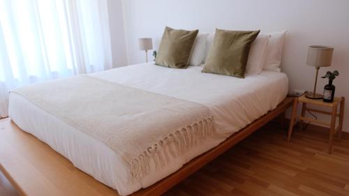 uma cama com lençóis brancos e almofadas num quarto em Peniche Supertubos Terrace em Peniche