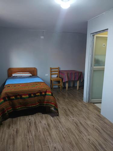 a bedroom with a bed and a table and a chair at El Amauta de los Andes Lodging Erik House in Huaraz